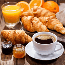 a cup of coffee croissants and orange juice on a table