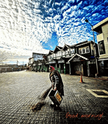 a woman is sweeping the sidewalk in front of a building that says ' emerald hotel '