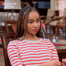 a woman in a red and white striped shirt is sitting at a table with the words assisted living on the bottom