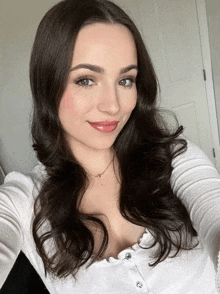 a woman wearing a white shirt and a necklace takes a selfie