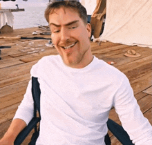 a man in a white shirt is sitting on a wooden deck