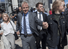 a man in a suit and tie holds hands with a woman in a white shirt