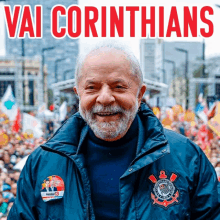 a man in a blue jacket is smiling in front of a crowd with the words vai corinthians above him