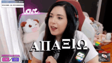 a woman wearing headphones is sitting in front of a screen that says aiiaeio on it