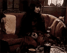 a woman in a gothic dress is sitting on a couch in a dark room .