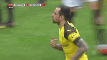 a soccer player wearing a yellow shirt that says dortmund is running on the field