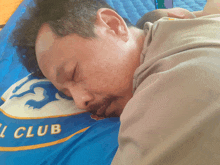 a man is sleeping on a blue pillow with the word club written on it