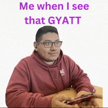 a man wearing glasses and a maroon hoodie with the words me when i see that gyatt on the bottom