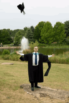 a man wearing a graduation cap and gown is throwing his cap in the air