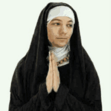 a nun is praying with her hands folded in front of her face .