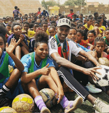 a man wearing a hat with the word icon on it sits in front of a crowd of children