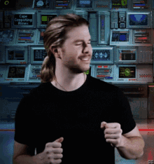 a man stands in front of a wall of computer monitors with one that says " free computing annex "