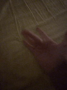 a close up of a person 's hand against a blanket