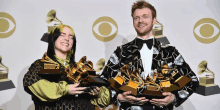 billie eilish and a man hold up their awards