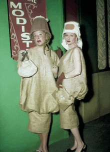 two women standing in front of a sign that reads modist