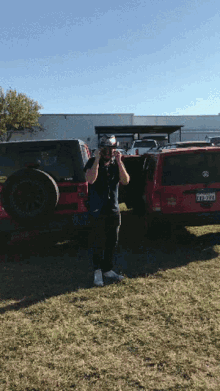 a man wearing a helmet stands in front of a red jeep with a texas license plate that says tt822