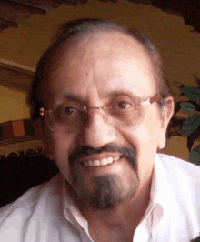 a man wearing glasses and a beard smiles for the camera