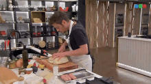 a man in an apron is cutting bread on a cutting board in a kitchen with #masterchefargentina written on the corner