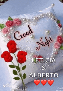 a white pillow with red roses and pearls and the words " good night leticia & alberto "