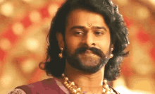 a man with a beard and long hair is wearing earrings and a gold necklace