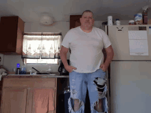 a man stands in front of a refrigerator with a calendar on it