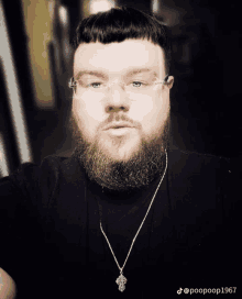 a man with a beard wearing glasses and a necklace with a cross on it