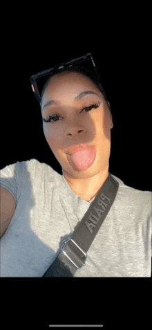 a woman is sticking her tongue out while wearing a gray shirt and a black strap that says always