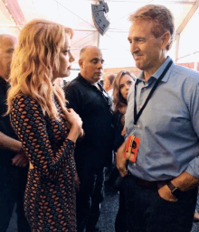 a man with a lanyard around his neck that says ' nbc ' on it is talking to a woman