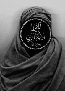 a black and white photo of a woman wearing a hijab with arabic writing on it