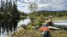 a woman sits on a blanket by a lake