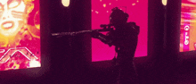 a man is holding a gun in front of a pink background .