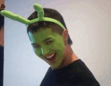 a man wearing a green mask and a green headband is making a funny face .