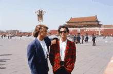 two men standing in front of a building with chinese writing