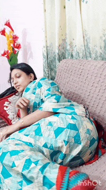 a woman in a blue dress is laying on a couch with her legs crossed .