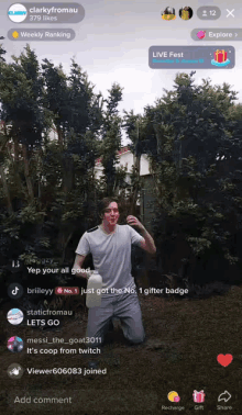 a man in a white shirt is kneeling down holding a milk carton in front of trees