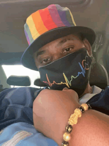 a man wearing a rainbow hat and a black face mask that says heartbeat