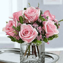 a vase filled with pink roses is sitting on top of a tray on a table .