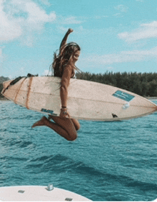 a woman is jumping in the air with a surfboard in her hand