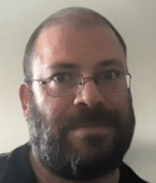 a man with a beard wearing glasses and a black shirt