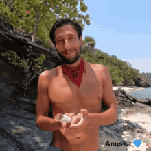 a shirtless man with a red bandana around his neck is holding a piece of paper with the name anuska on the bottom