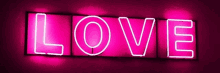 a neon sign that says love is lit up in pink