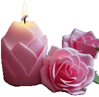 a candle in the shape of a flower is next to pink roses