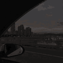 a car is driving down a highway at night with a view of a city skyline .