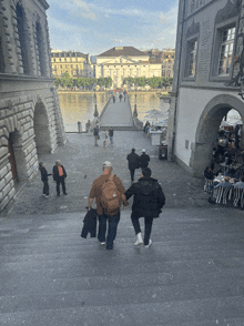 a couple walking down a set of stairs in front of a building with a sign that says ' bank ' on it