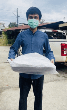 a man wearing a mask is holding a large white bag in front of a white truck