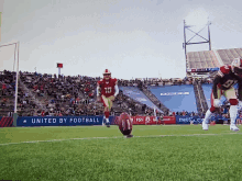 a football player kicking a ball in front of a united by football banner