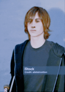 a young man wearing a black shirt that says istock is holding a skateboard