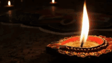 a close up of a lit candle on a table in a dark room .