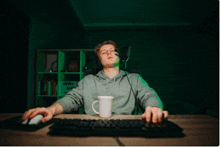 a man wearing headphones and a headset is sitting at a desk with a keyboard and mouse .