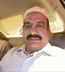 a man with a mustache wearing a white hat is sitting in a car